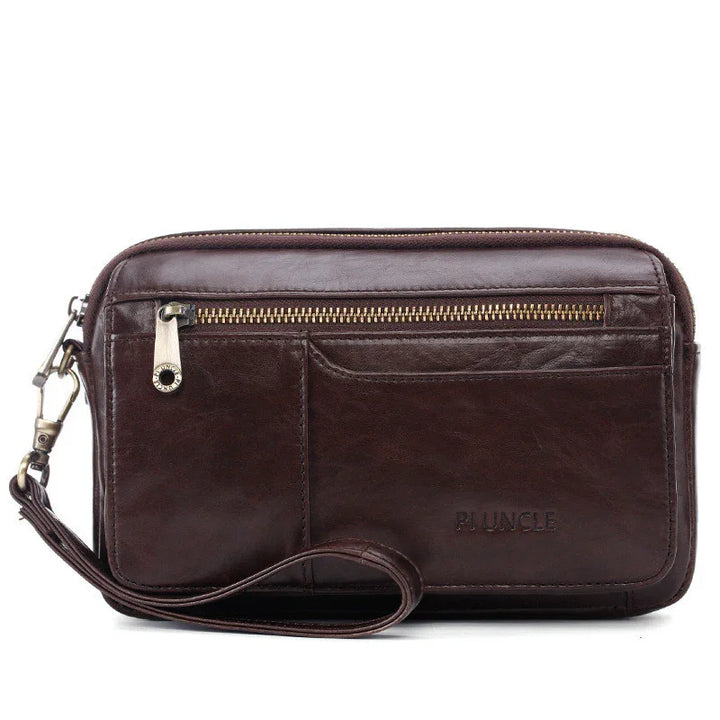 Dark brown leather wristlet clutch with front zipper pocket and detachable strap on white background