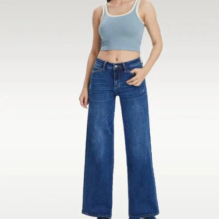 Woman wearing light blue crop top and high-waist wide leg blue jeans on white background