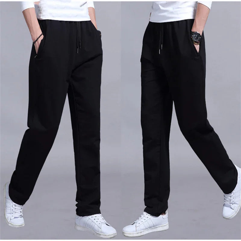 Male model wearing black casual drawstring pants with side pockets and white sneakers