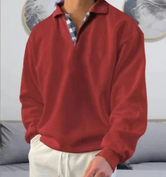 Man wearing red long-sleeve shirt with plaid collar detail, paired with cream pants indoors