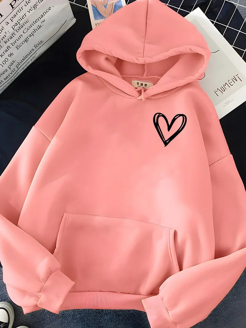 Pink hoodie with black heart graphic on chest, front pocket, and hood on dark surface