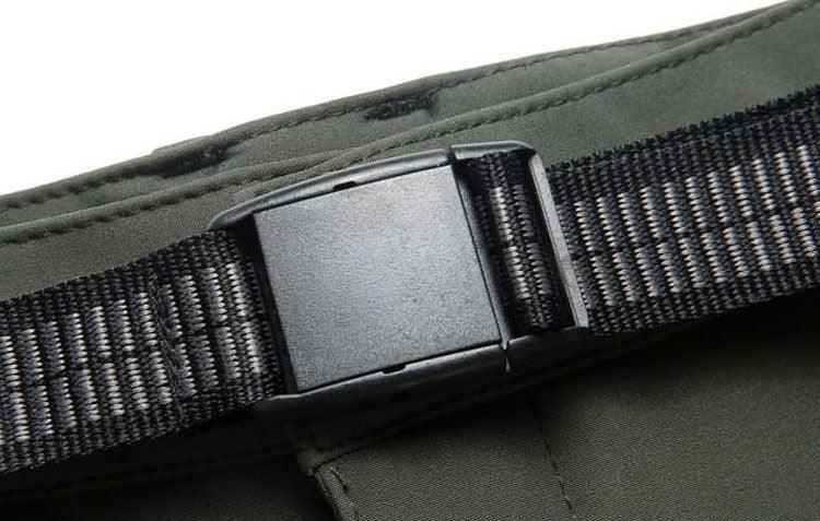 Close-up of a black plastic buckle on a woven nylon strap attached to olive green fabric
