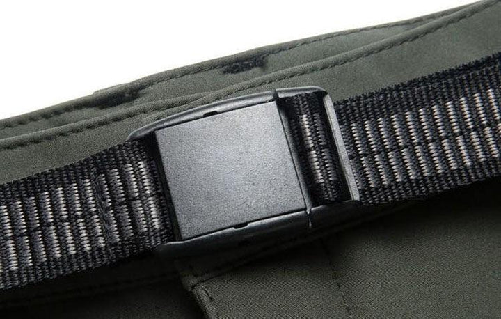 Close-up of a black plastic buckle on a woven nylon strap attached to olive green fabric