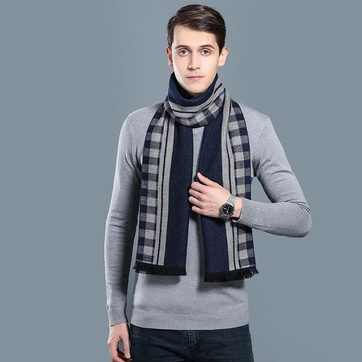 Young man wearing a navy and gray checkered scarf over a light gray sweater, posing against a gray background