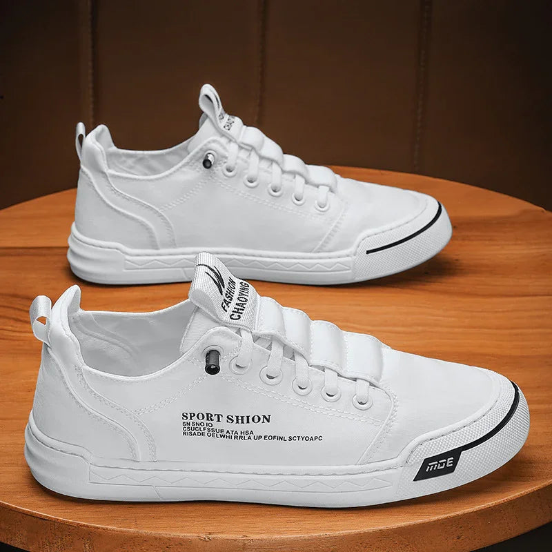 White casual sport shoes with black text and rubber sole placed on wooden surface