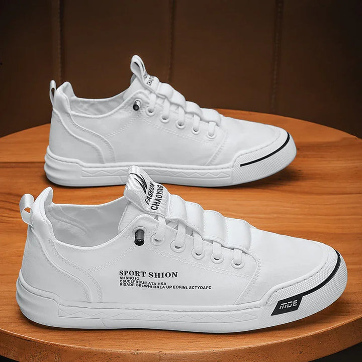 White casual sport shoes with black text and rubber sole placed on wooden surface