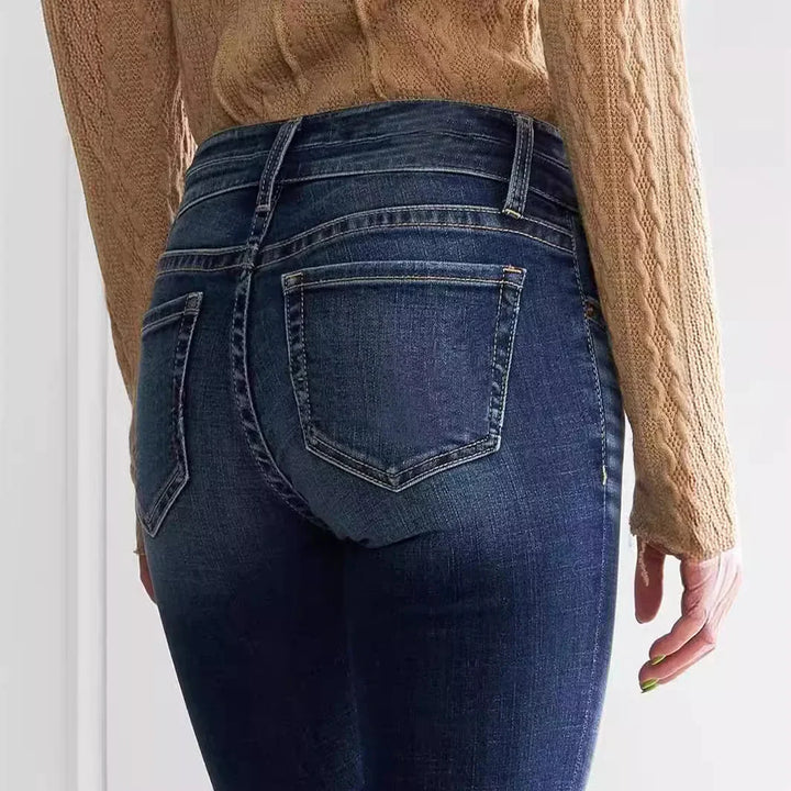 Back view of person wearing dark blue denim jeans and a tan cable knit sweater