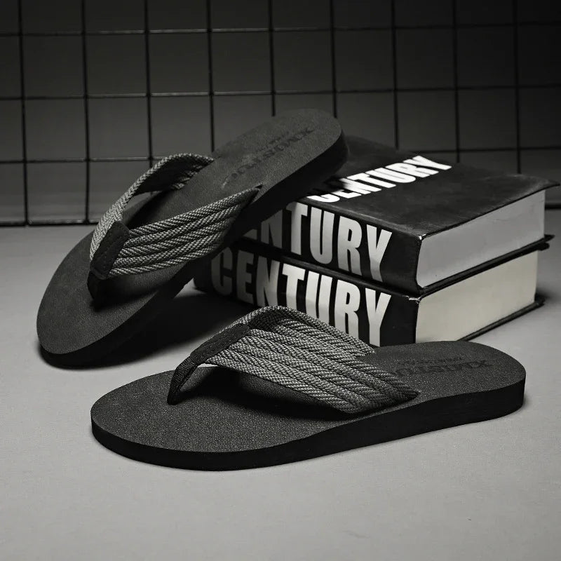 Black flip-flops with braided gray straps placed near stacked books with "CENTURY" text on covers