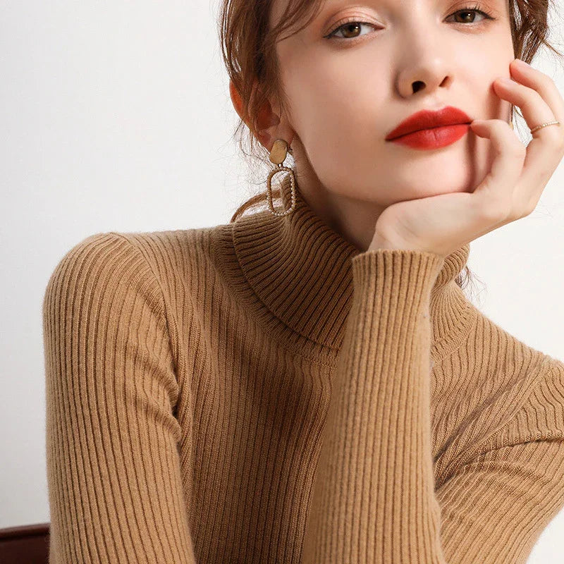 Woman wearing a camel ribbed turtleneck sweater and gold geometric earrings with red lipstick