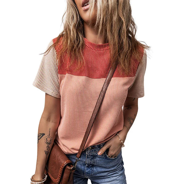 Woman wearing colorblock ribbed knit top in red and peach with denim jeans and brown crossbody bag