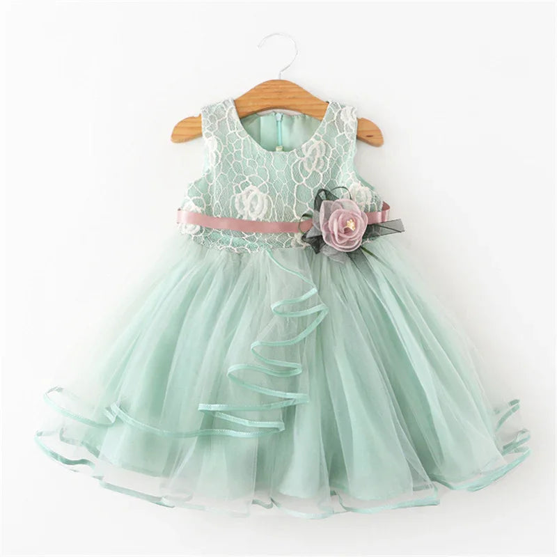 Light green sleeveless baby dress with lace top, tulle skirt, pink belt, and flower decoration
