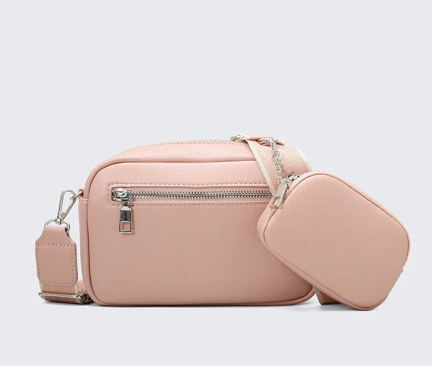 Pink leather crossbody bag with front zipper pocket and attached smaller pouch on adjustable strap