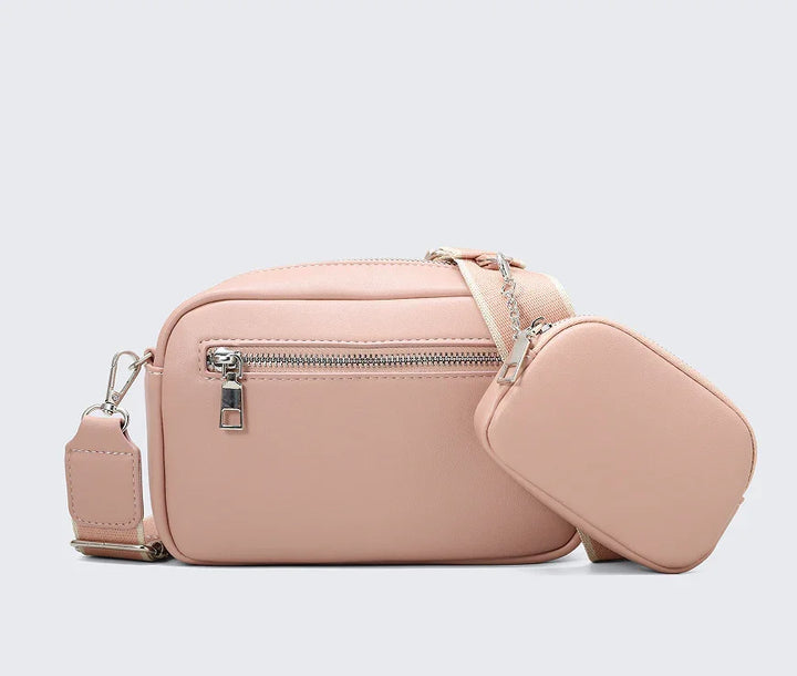 Pink leather crossbody bag with front zipper pocket and attached smaller pouch on adjustable strap