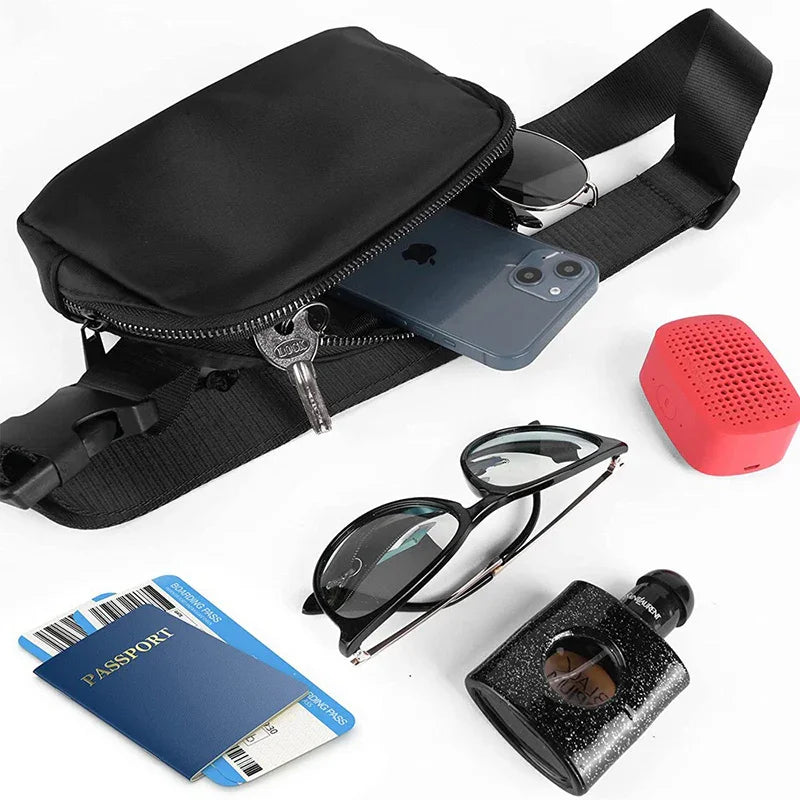 Black waist bag with zipper open showing smartphone, keys, sunglasses, red portable speaker, passport, and black cologne bottle