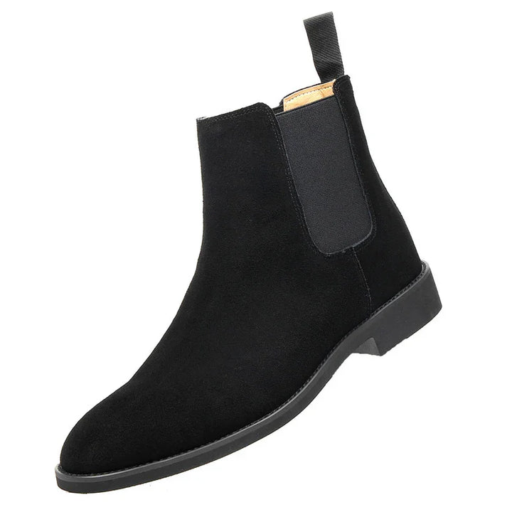 Black suede Chelsea boot with elastic side panel and pull tab on white background