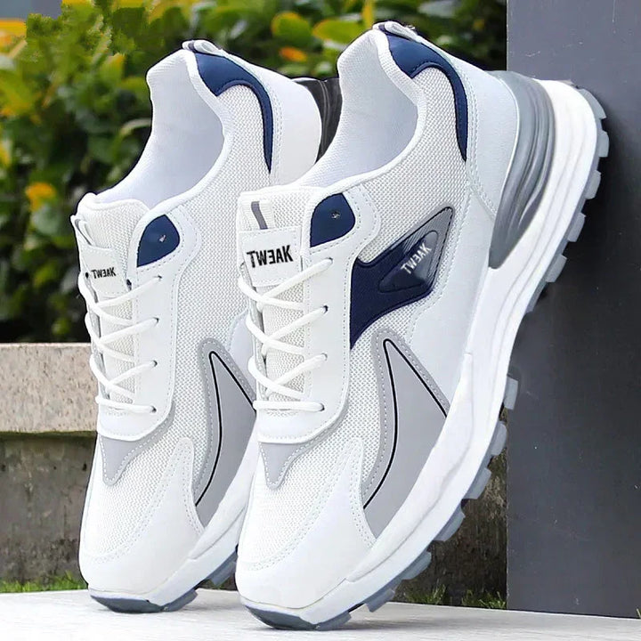 White and navy Tweak brand athletic sneakers with mesh and synthetic overlays, displayed outdoors