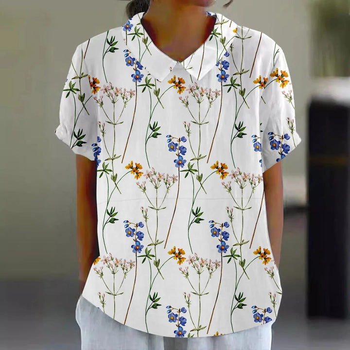 Woman wearing white short-sleeve blouse with colorful floral print and a pointed collar