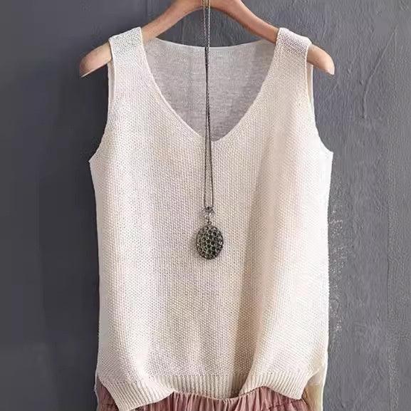 Cream sleeveless knitted top on wooden hanger with silver pendant necklace against gray wall