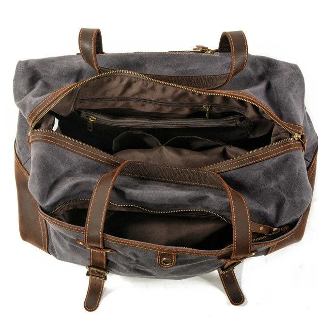 Open gray canvas and brown leather travel duffel bag with multiple zippered compartments and handles