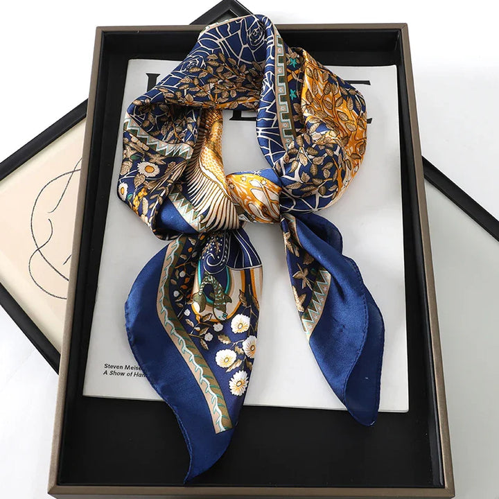 Silk scarf with floral and abstract gold patterns on blue background displayed in black frame