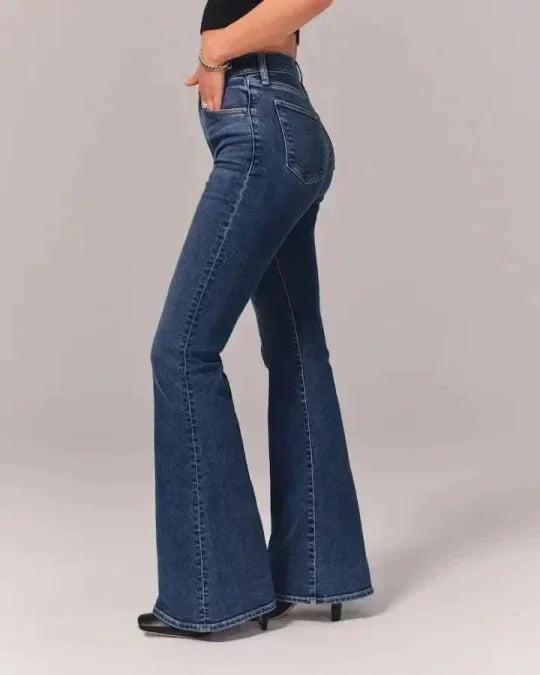 Side view of woman wearing high-waisted dark blue flared jeans with black heels and black top