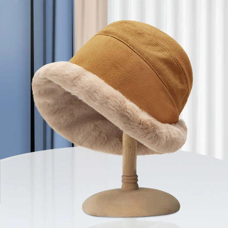 Brown winter bucket hat with soft beige faux fur trim on wooden hat stand