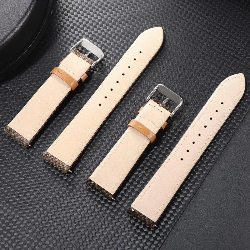 Four beige leather watch straps with brown accents and silver buckles on black textured surface