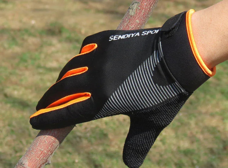 Hand wearing black and orange SENDIYA SPORT glove gripping a tree branch outdoors