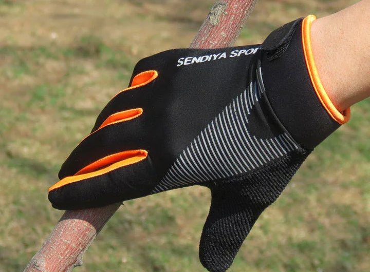 Hand wearing black and orange SENDIYA SPORT glove gripping a tree branch outdoors