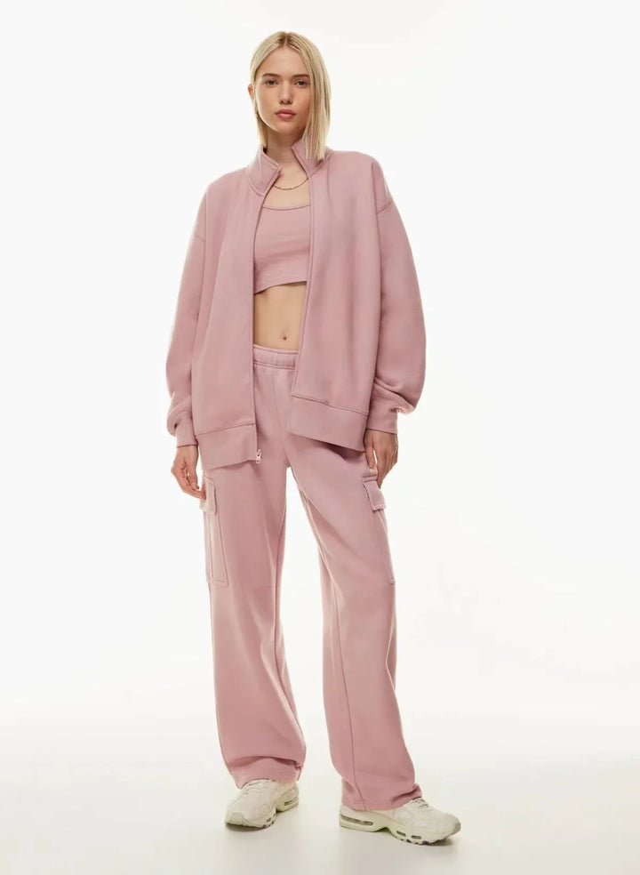 Woman in light pink lounge set with cargo pants, open jacket, crop top, and white sneakers.