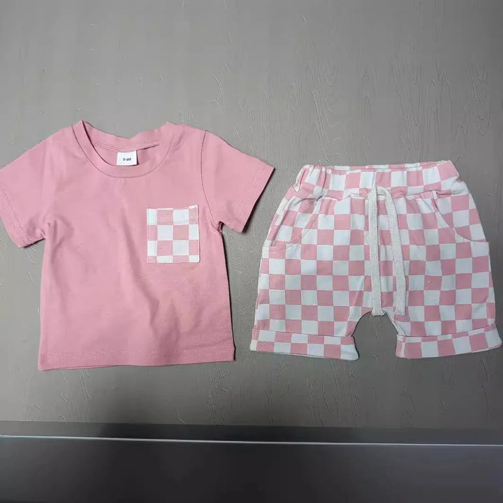 Pink toddler outfit with checkerboard pocket t-shirt and matching shorts on gray surface