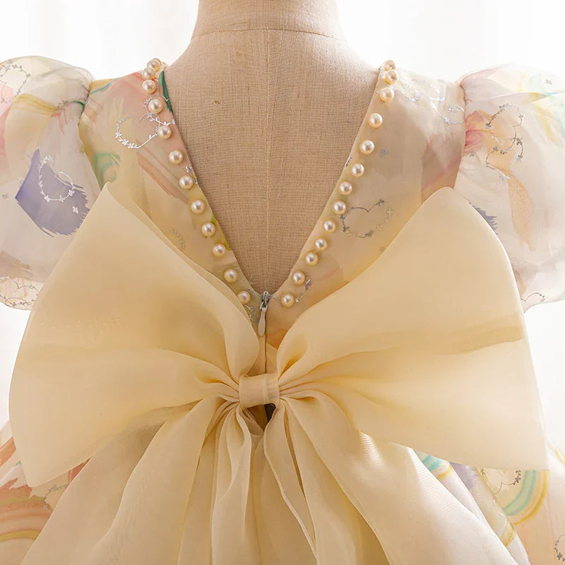 back view of pastel dress with pearl trim, puff sleeves, and large sheer bow on mannequin