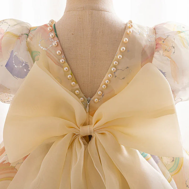 back view of pastel dress with pearl trim, puff sleeves, and large sheer bow on mannequin