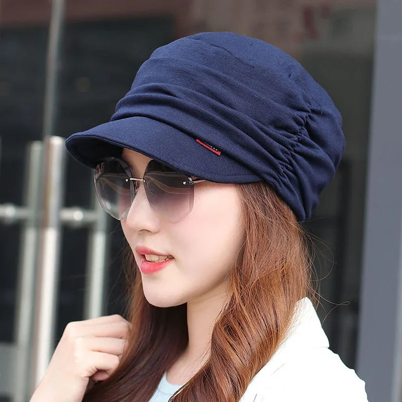Young woman wearing navy blue ruched cap and oversized sunglasses outdoors