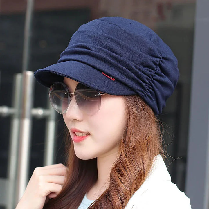 Young woman wearing navy blue ruched cap and oversized sunglasses outdoors