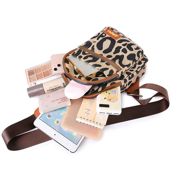 Leopard print crossbody bag with brown strap, holding phone, tablet, makeup, notebook, and power bank