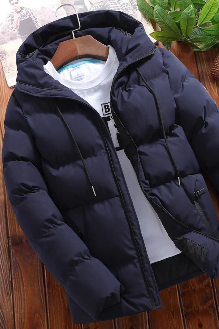 Navy blue puffer jacket with hood and drawstrings over white graphic t-shirt on wooden surface