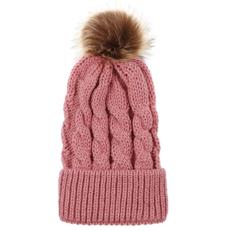 Pink cable knit winter beanie hat with a brown faux fur pompom on top