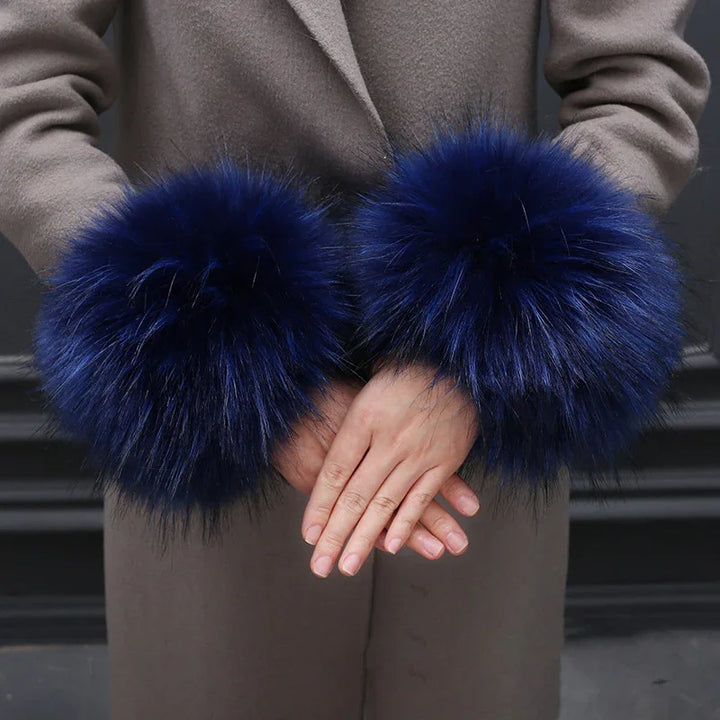 Person wearing a grey coat with large, fluffy navy blue fur cuffs on the sleeves