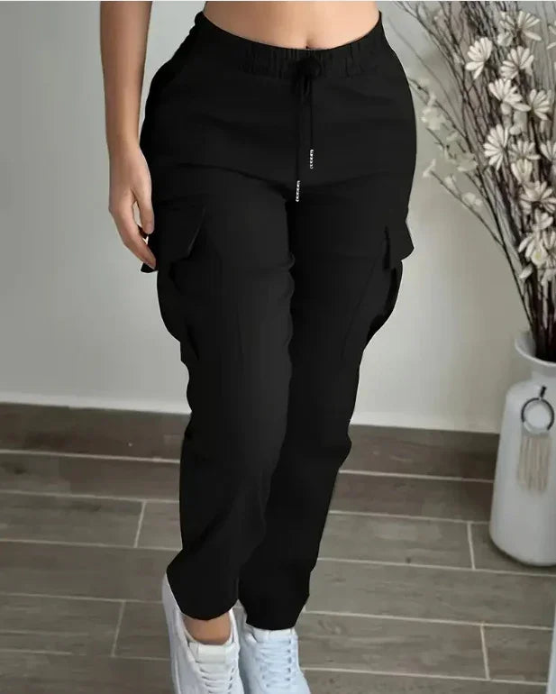 Person wearing black cargo jogger pants with drawstring waist and white sneakers on tiled floor