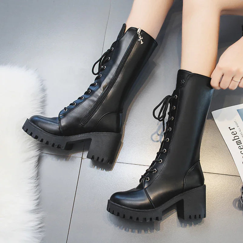 Black leather mid-calf lace-up boots with chunky heels and side zippers on gray tiled floor