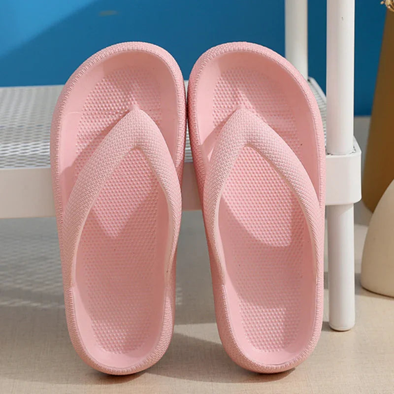 Pair of light pink textured rubber flip flop slippers on beige floor near white metal rack