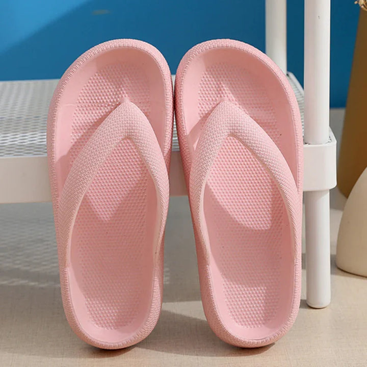 Pair of light pink textured rubber flip flop slippers on beige floor near white metal rack