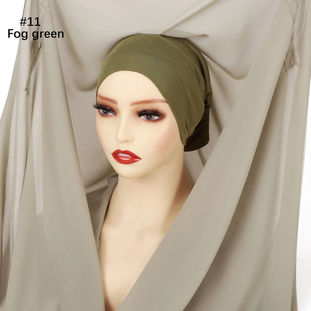Mannequin wearing fog green headscarf surrounded by matching beige fabric backdrop