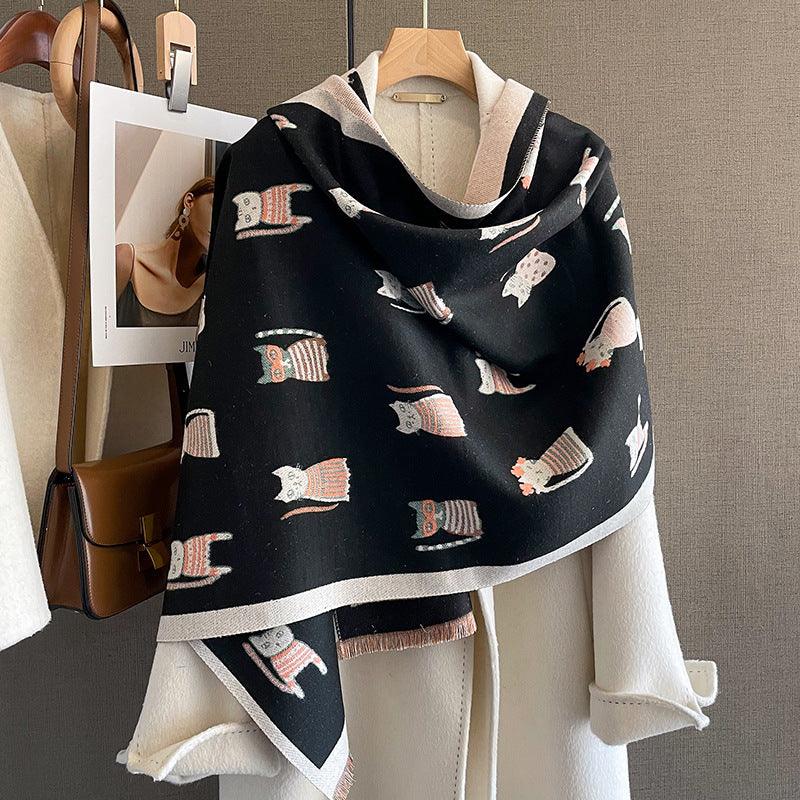 Black scarf with orange and white owl patterns draped over a white coat on wooden hanger