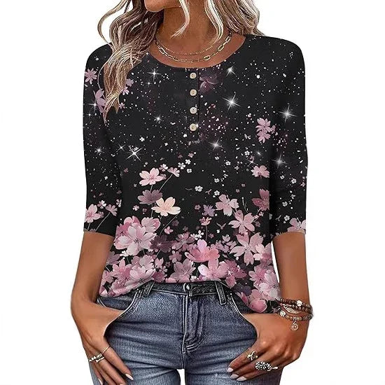 Woman wearing black floral print Henley top with pink flowers and starry design, paired with blue jeans