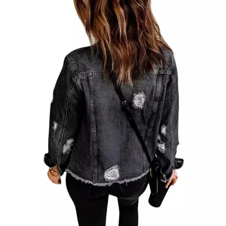 Back view of woman wearing distressed black denim jacket and black pants with crossbody bag