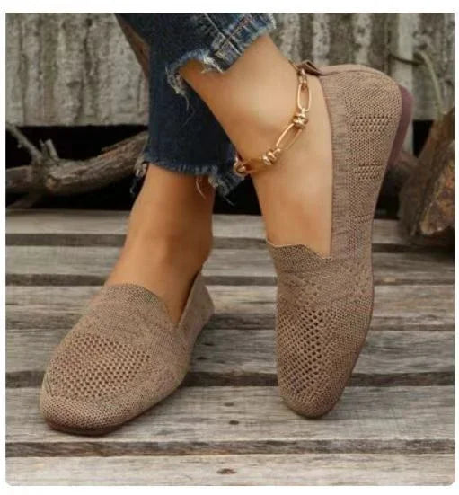 Brown knitted slip-on flats worn with blue cropped jeans and gold anklet on wooden floor