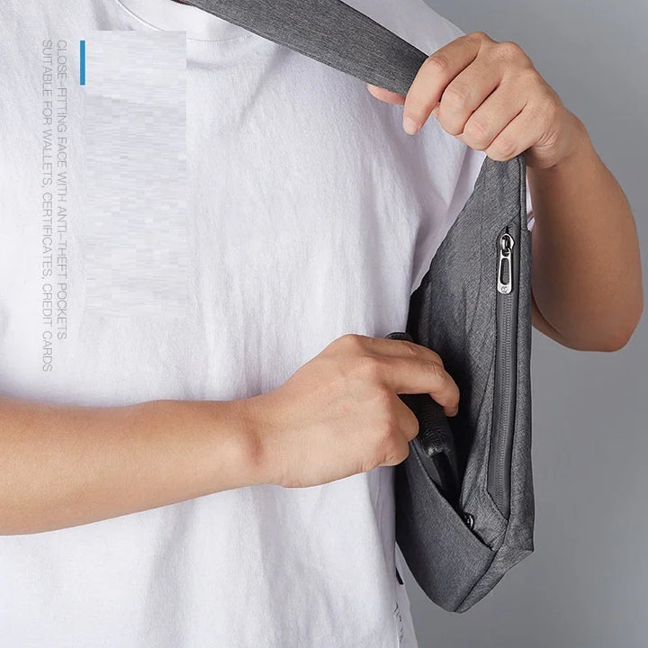 Person wearing a white t-shirt holding a gray anti-theft crossbody bag with zipper pocket