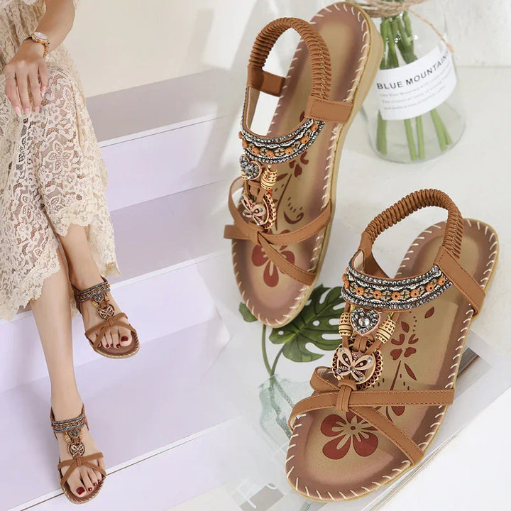 Brown women sandals with beaded and floral details, worn with lace skirt on white stairs